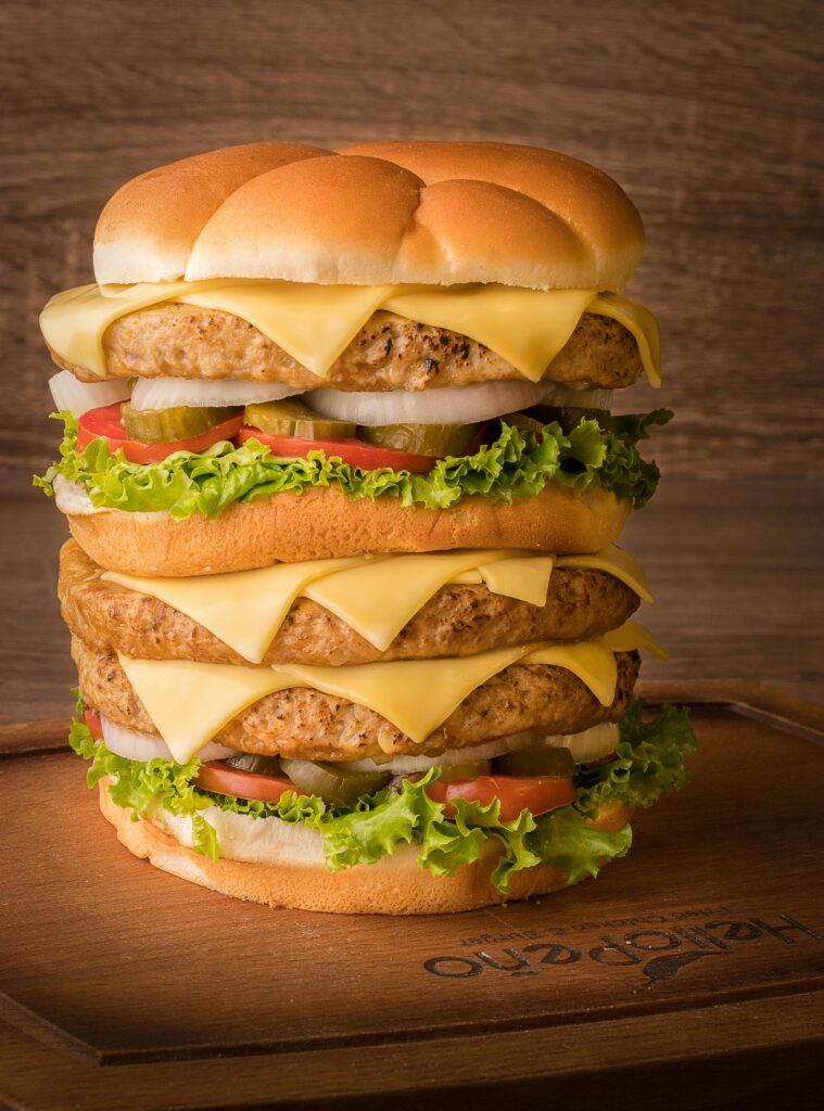 pexels-photo-14709734-14709734 Mouth-watering triple stack cheeseburger with fresh toppings on a rustic wooden board.
